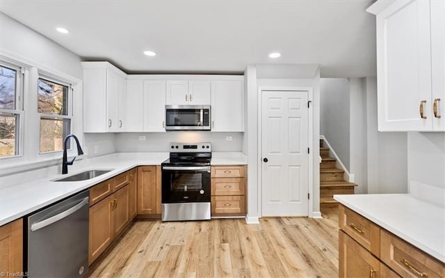 kitchen featuring sink, light wood-type flooring, white cabinets, and appliances with stainless steel finishes