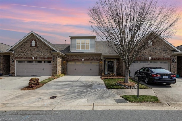 view of front of home featuring concrete driveway, a garage, and brick siding