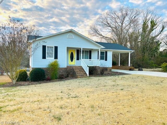 ranch-style home with a front yard and covered porch