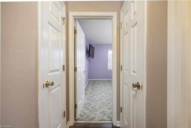 hallway featuring dark colored carpet