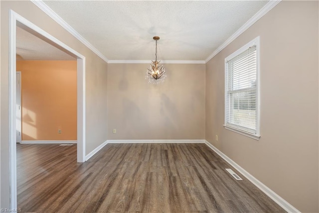 spare room featuring a notable chandelier, a textured ceiling, dark wood-type flooring, and ornamental molding