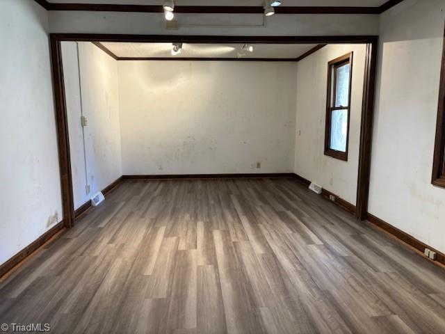 empty room with hardwood / wood-style floors and crown molding