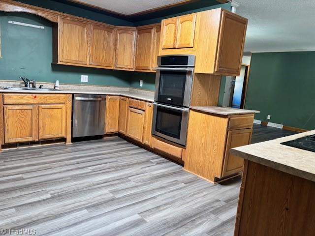 kitchen featuring crown molding, appliances with stainless steel finishes, sink, and light wood-type flooring