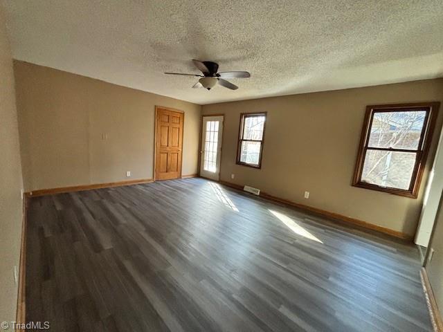 empty room with dark wood-type flooring, a textured ceiling, and ceiling fan