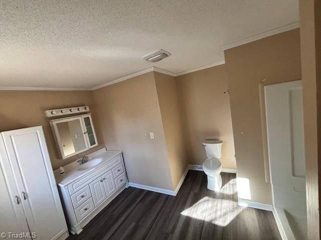 bathroom featuring crown molding, hardwood / wood-style floors, vanity, a textured ceiling, and toilet