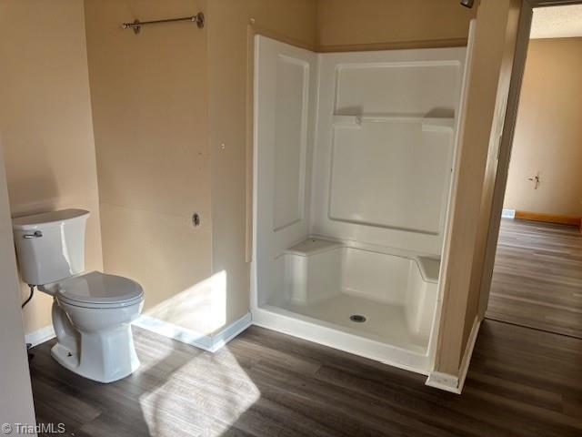 bathroom featuring hardwood / wood-style flooring, a shower, and toilet