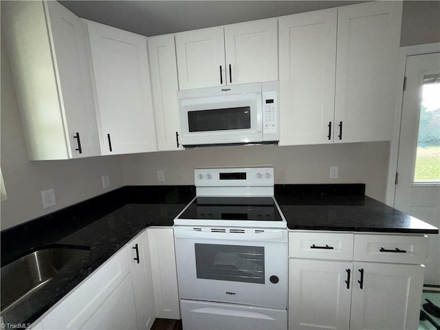 kitchen featuring sink, white appliances, white cabinetry, and dark stone counters