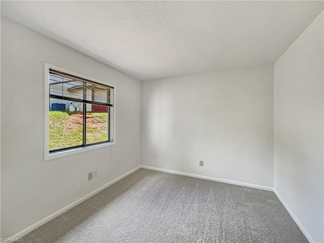 empty room with carpet flooring, baseboards, and a textured ceiling