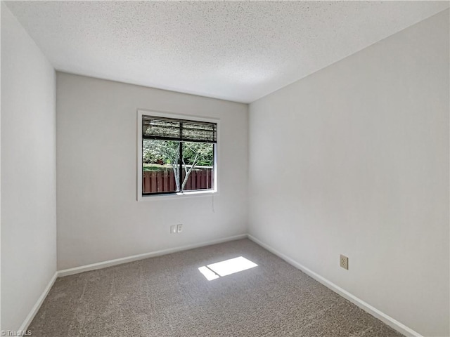 carpeted spare room with a textured ceiling and baseboards