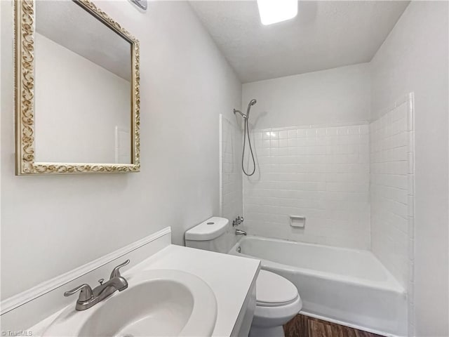 bathroom with toilet, wood finished floors, tub / shower combination, and vanity