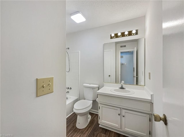 full bathroom with a textured ceiling, toilet, wood finished floors, vanity, and bathing tub / shower combination
