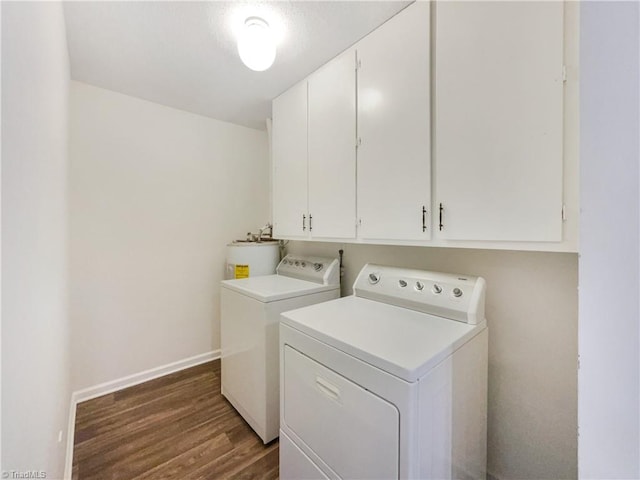 clothes washing area with washing machine and clothes dryer, cabinet space, baseboards, dark wood finished floors, and water heater