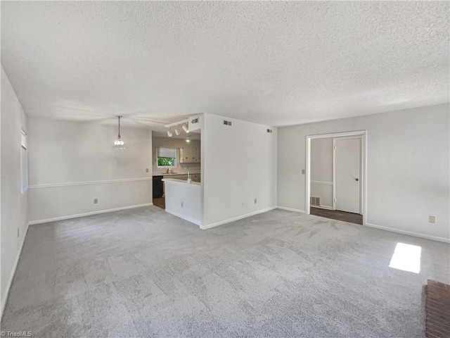 unfurnished living room featuring a textured ceiling, carpet floors, a chandelier, and baseboards