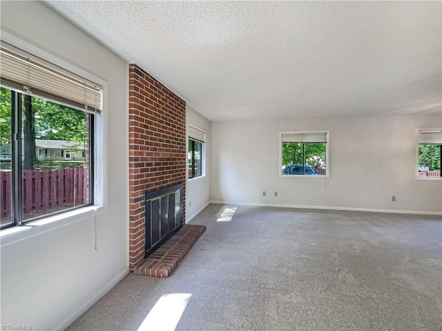 unfurnished living room featuring a textured ceiling, a brick fireplace, carpet flooring, and baseboards