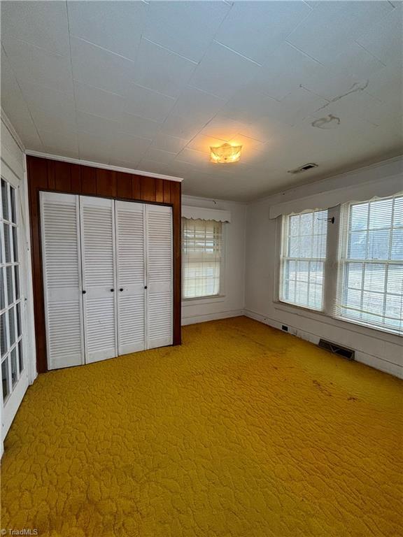 unfurnished bedroom with wooden walls and carpet