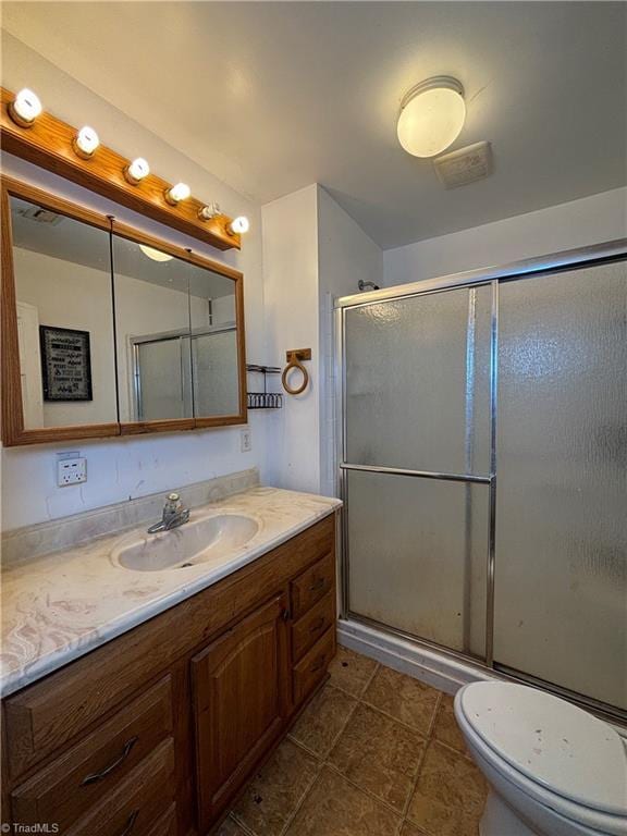 bathroom with tile patterned floors, vanity, toilet, and an enclosed shower