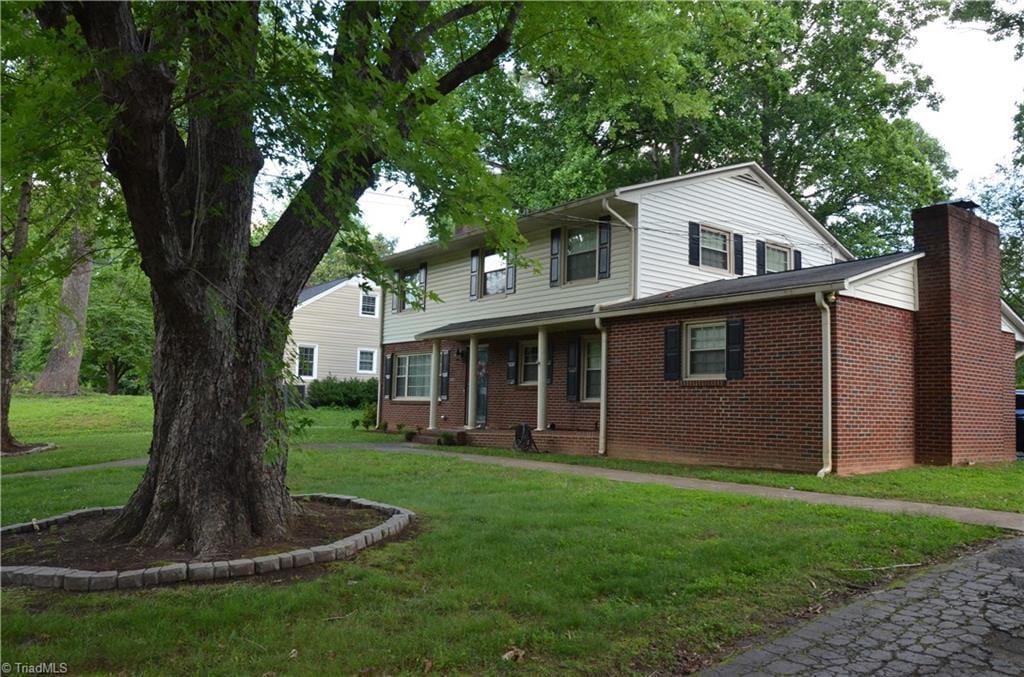 1613 Normandy Ln, Winston-Salem, NC 27103 - view of front of home featuring a front lawn, brick siding, and a chimney
