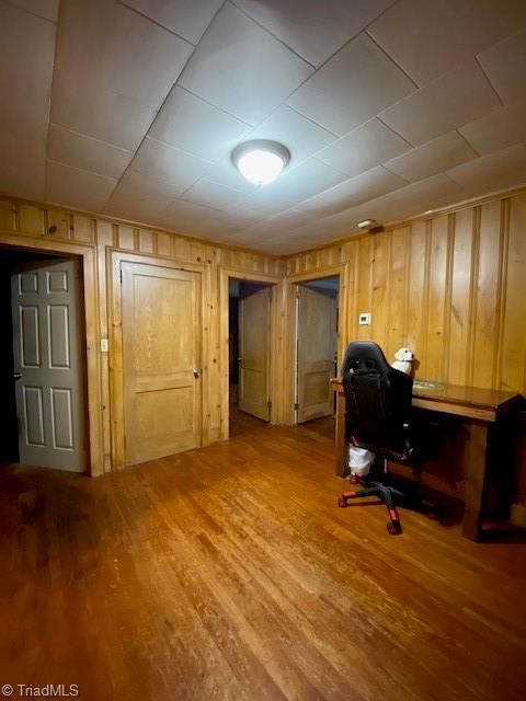 home office with hardwood / wood-style floors and wooden walls