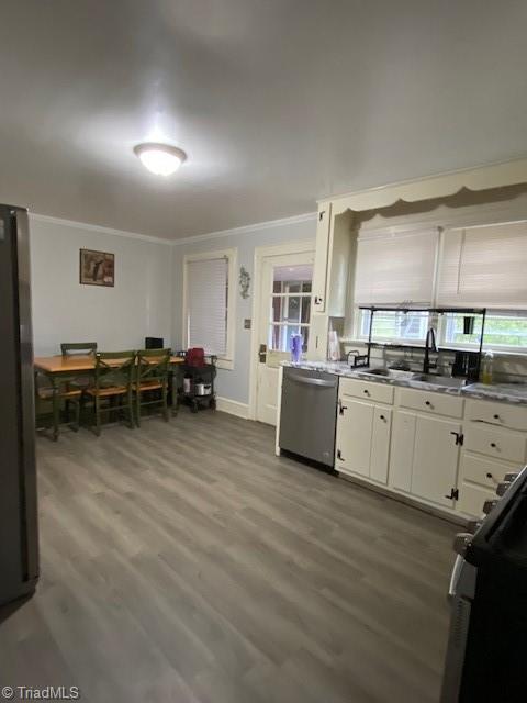 kitchen with hardwood / wood-style flooring, ornamental molding, white cabinets, and appliances with stainless steel finishes