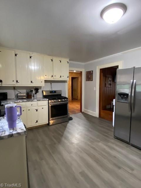 kitchen with hardwood / wood-style flooring, appliances with stainless steel finishes, and white cabinets