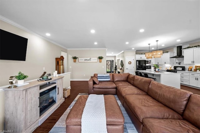 living room with baseboards, ornamental molding, recessed lighting, dark wood-style floors, and a glass covered fireplace