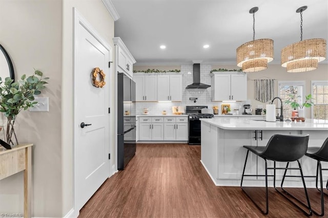 kitchen featuring ornamental molding, black appliances, wall chimney exhaust hood, and a sink