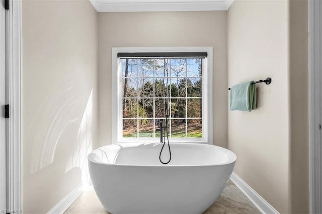 full bathroom with crown molding, a freestanding tub, and baseboards