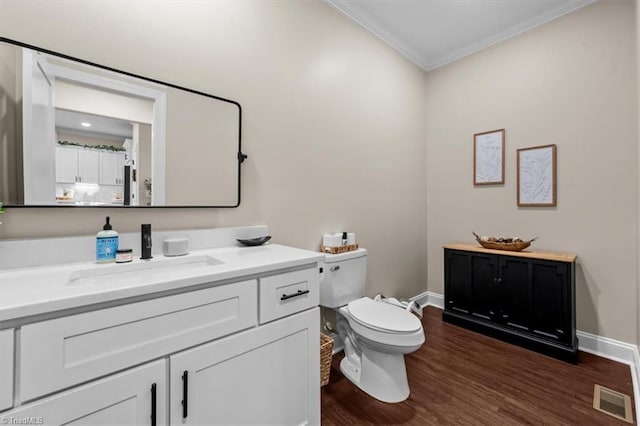 bathroom with visible vents, toilet, ornamental molding, wood finished floors, and vanity