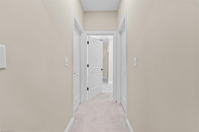 hall with baseboards and light carpet