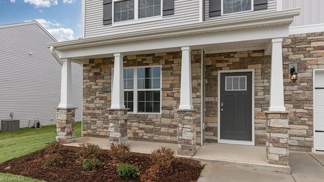 property entrance with cooling unit, stone siding, board and batten siding, and a porch