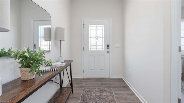 doorway featuring baseboards and wood finished floors