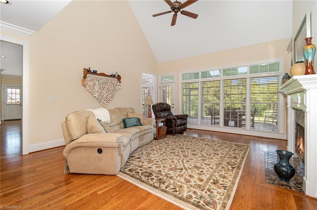 7469 Henson Forest Dr, Summerfield, NC 27358 - living area featuring ceiling fan, a warm lit fireplace, wood finished floors, high vaulted ceiling, and baseboards