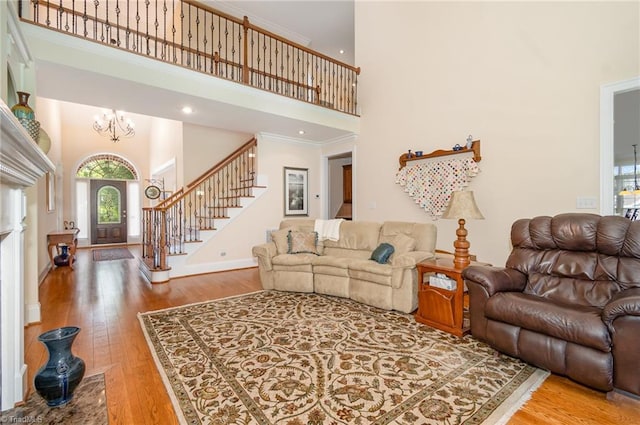 7469 Henson Forest Dr, Summerfield, NC 27358 - living room with a high ceiling, wood finished floors, stairway, a chandelier, and baseboards