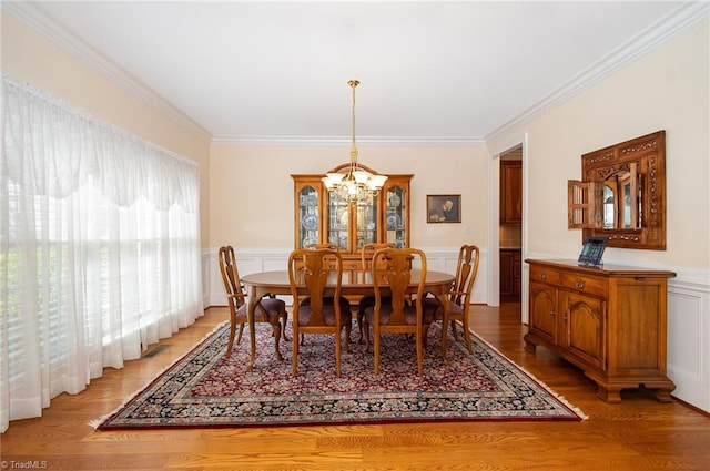 7469 Henson Forest Dr, Summerfield, NC 27358 - dining room with ornamental molding, a chandelier, a wainscoted wall, a decorative wall, and light wood-style floors