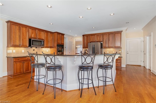 7469 Henson Forest Dr, Summerfield, NC 27358 - kitchen with appliances with stainless steel finishes, a kitchen bar, crown molding, backsplash, and dark countertops
