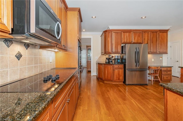 7469 Henson Forest Dr, Summerfield, NC 27358 - kitchen with appliances with stainless steel finishes, crown molding, light wood-type flooring, brown cabinets, and tasteful backsplash