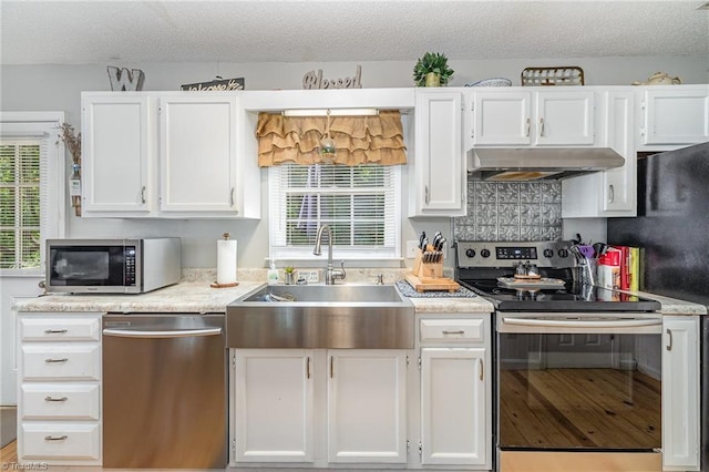kitchen featuring a sink, appliances with stainless steel finishes, under cabinet range hood, and white cabinetry