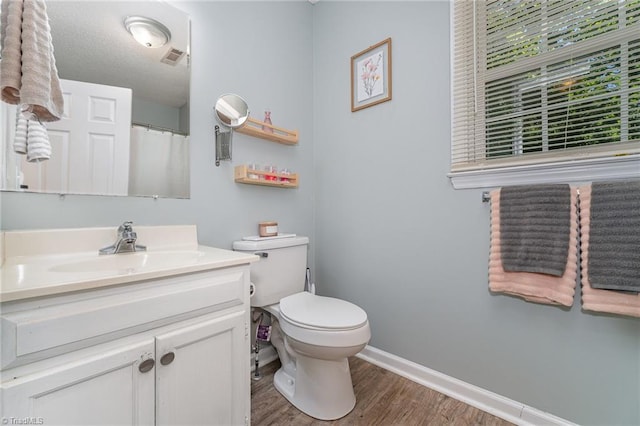 full bath featuring visible vents, vanity, wood finished floors, toilet, and baseboards