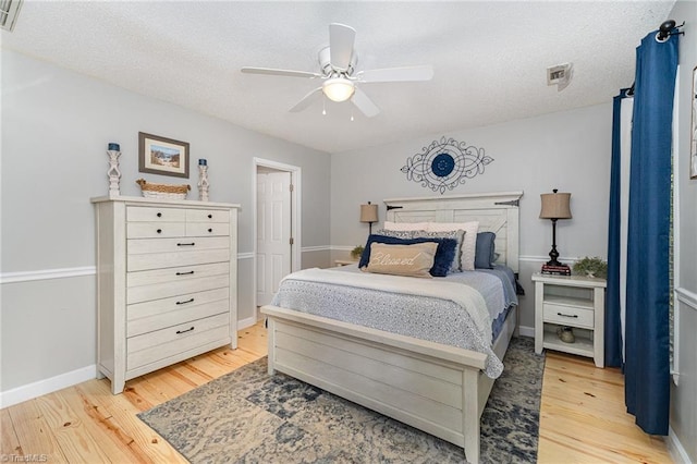 bedroom featuring a textured ceiling, baseboards, a ceiling fan, and light wood-style flooring