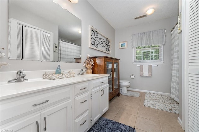 full bath with visible vents, a sink, double vanity, and toilet