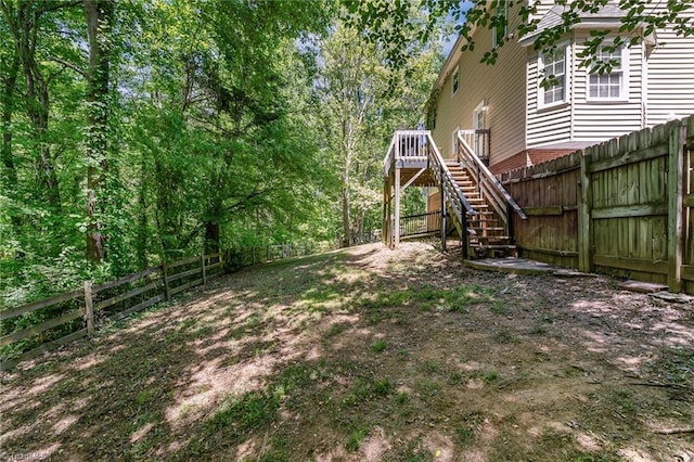 view of yard featuring a deck, stairs, and a fenced backyard