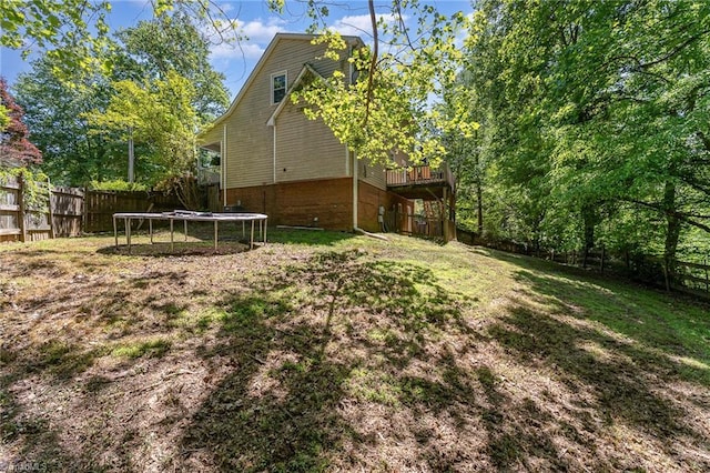 view of yard with a fenced backyard, a trampoline, and a deck