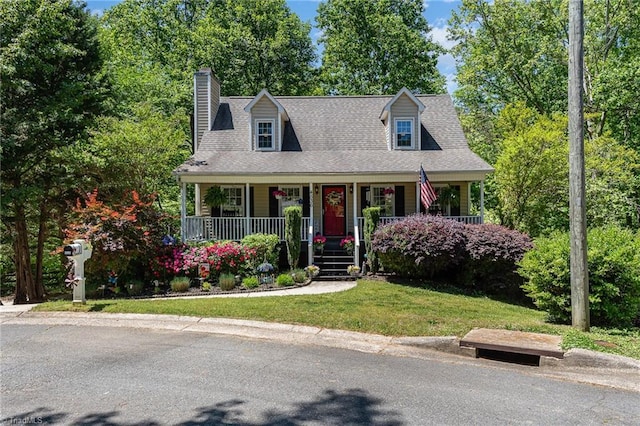 cape cod-style house featuring a chimney, a porch, and a front yard