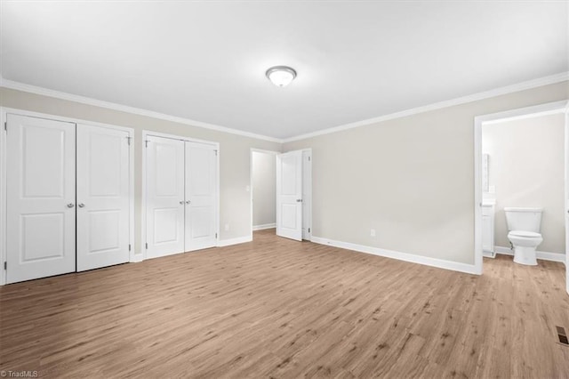 2517 Hopewell Friends Rd, Asheboro, NC 27205 - unfurnished bedroom featuring multiple closets, light wood-style flooring, crown molding, and connected bathroom