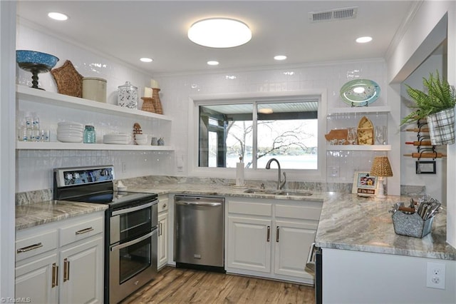 kitchen with visible vents, crown molding, appliances with stainless steel finishes, a sink, and open shelves