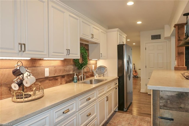 kitchen featuring a sink, freestanding refrigerator, tasteful backsplash, white cabinets, and recessed lighting
