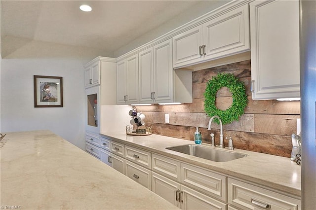 kitchen with backsplash, a sink, white cabinetry, and recessed lighting