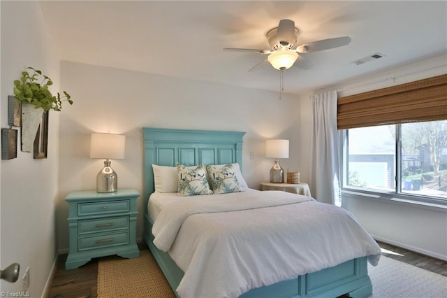 bedroom with baseboards, visible vents, dark wood-type flooring, and a ceiling fan