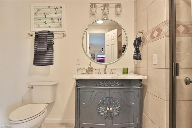 bathroom featuring tile patterned flooring, vanity, toilet, a shower with door, and baseboards