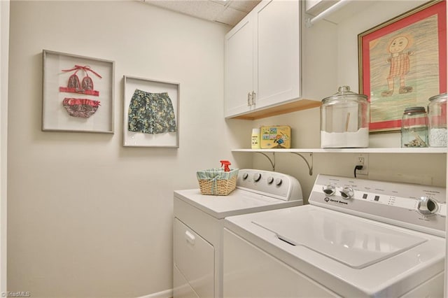 washroom featuring washer and clothes dryer, cabinet space, and baseboards
